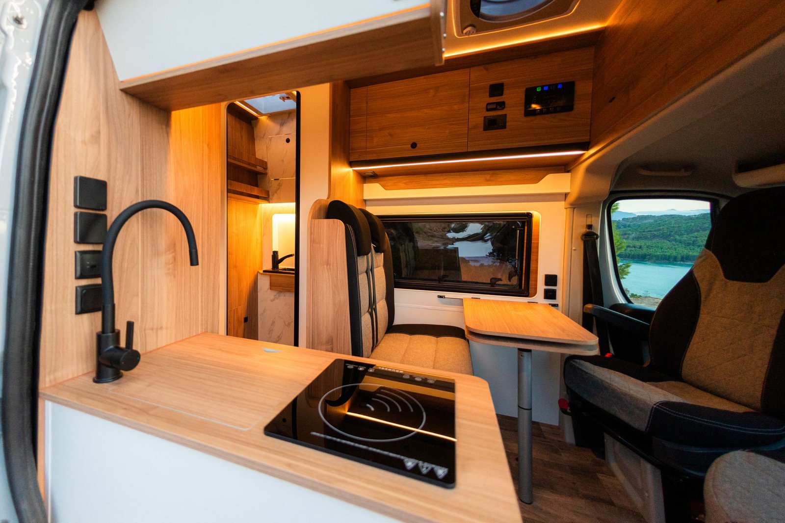 Interior con cocina de inducción, grifo negro, comedor y cabina, con vistas al embalse por las ventanas