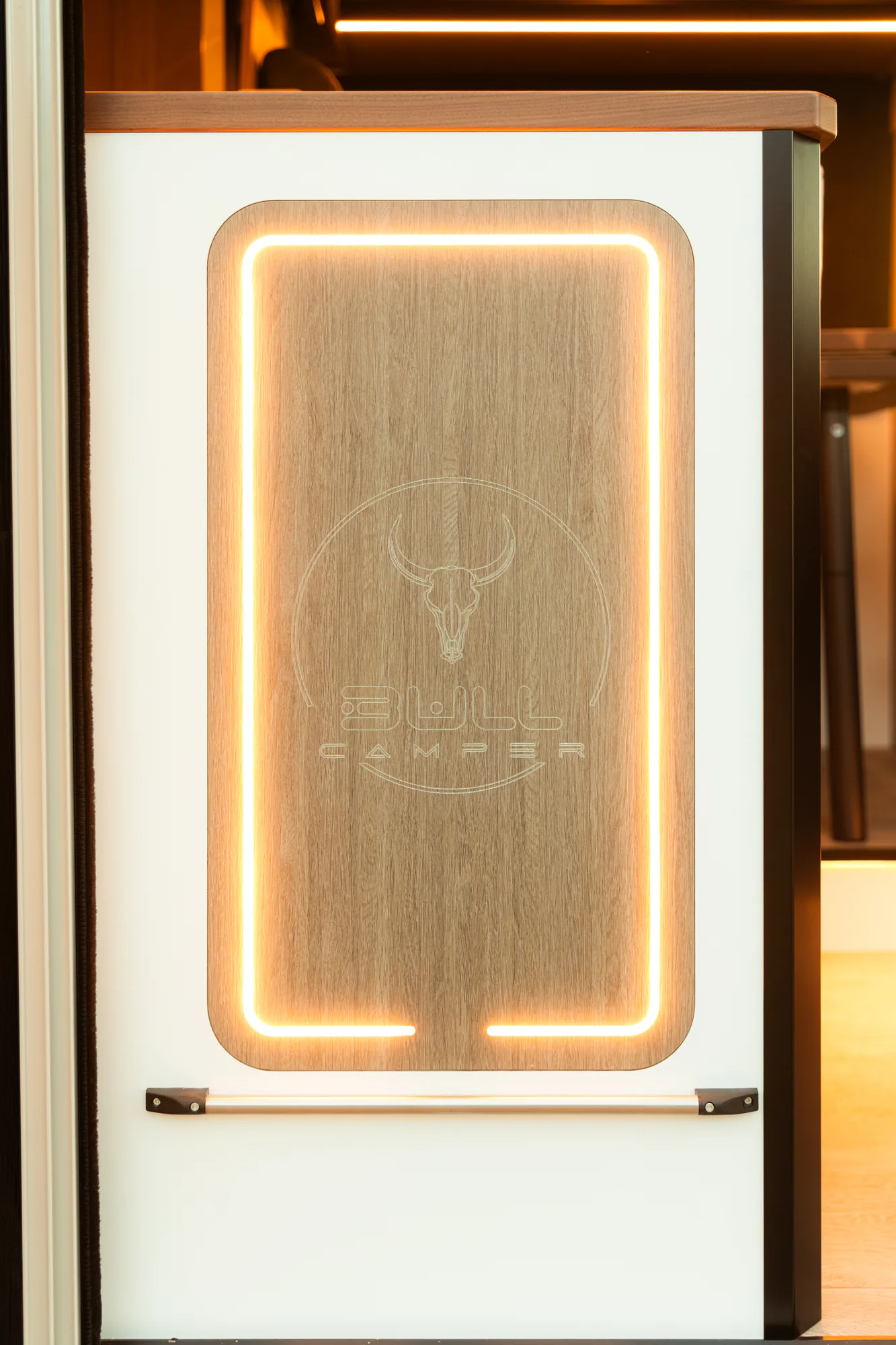 Puerta de madera con el logo Bullcamper grabado y marco iluminado con luz LED